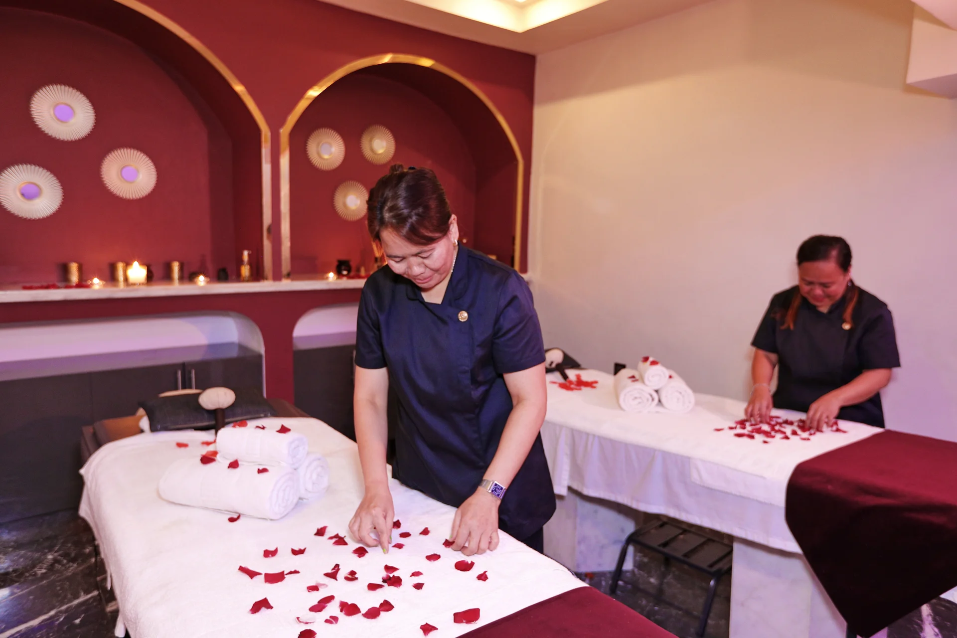 Deux thérapeutes préparent les tables de massage dans une cabine bordeaux du spa Orélia