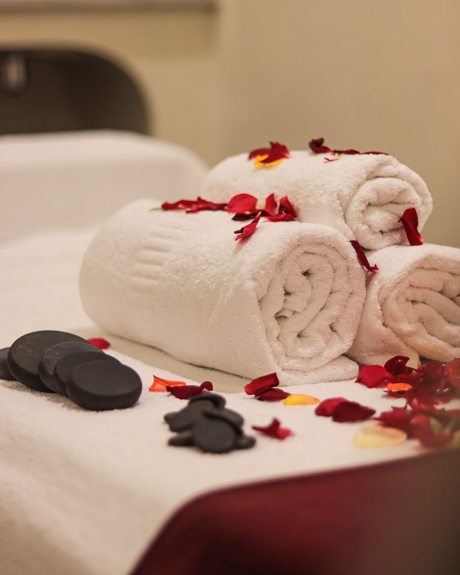 Serviettes roulées, pétales et pochons disposés sur une table de soin du spa Orélia